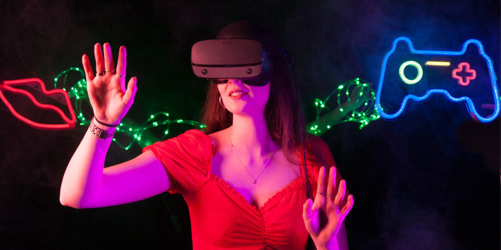 Student with VR headset on stood infront of neon signs