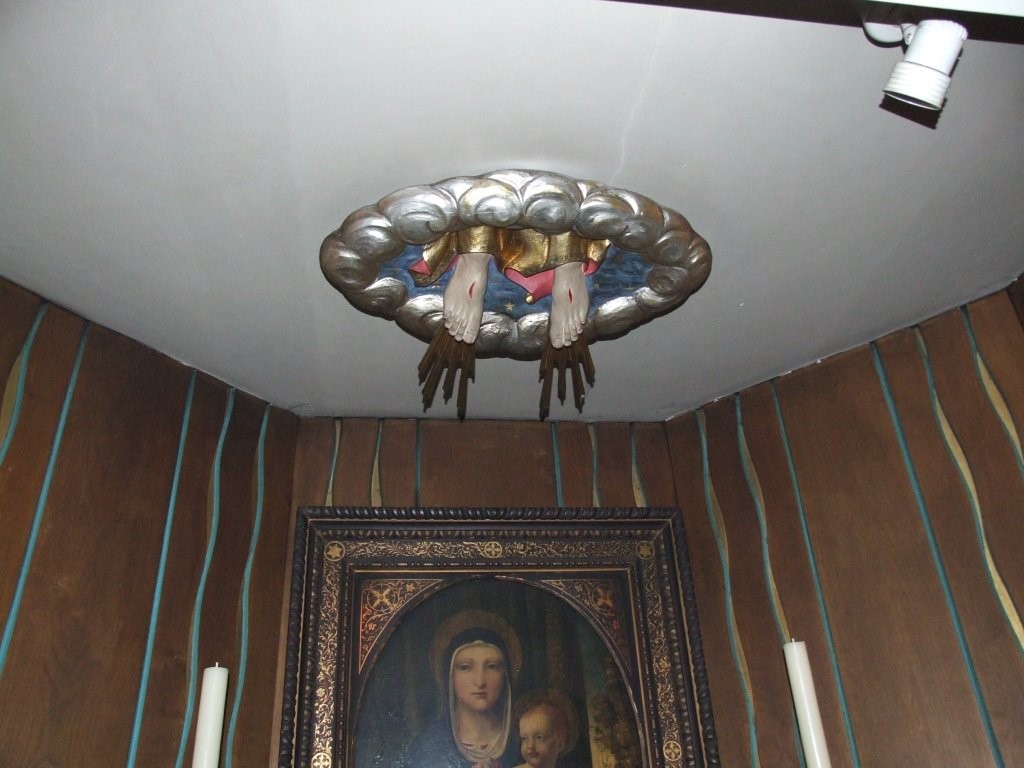 A chapel with a scupture of a pair of feet disappearing into the ceiling