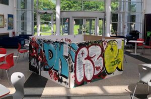 Graffiti on 4 boards creating a cube structure inside a campus atrium.