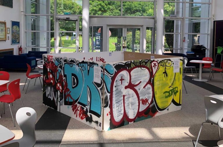 Graffiti on 4 boards creating a cube structure inside a campus atrium.