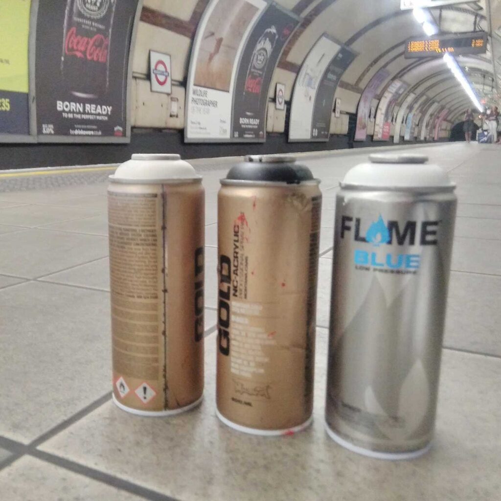 Spray cans sitting on the platform in a tube station.