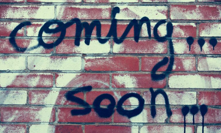 Coming soon written in graffiti on a wall.