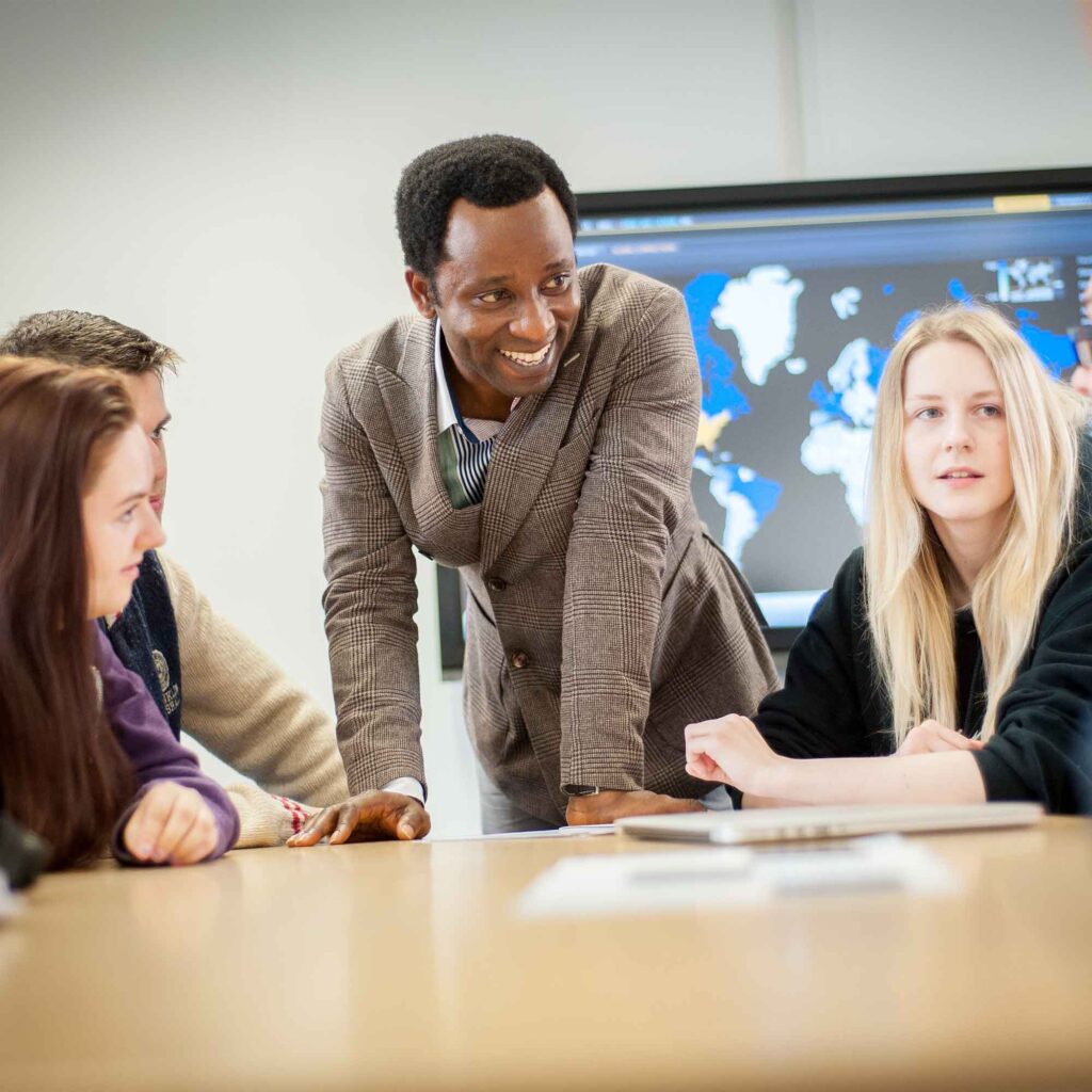 Charles Afriyie in the Business School trading room talking to students.