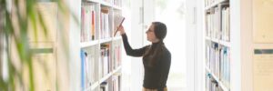 Student selecting a book from a bookshelf.