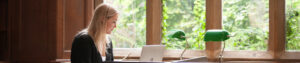 Student using a laptop by a window.